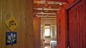 A wooden hallway leading to a bedroom with a bed and a chair. - Casa El Pelaire (Perarrua)