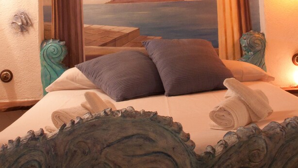 A bedroom with a bed, pillows, a decorative headboard, and a mural of a landscape. - Casa El Pelaire (Perarrua)