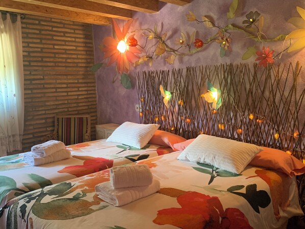 A room with a brick wall, a bed with floral bedding, and a decorative wall with lights.