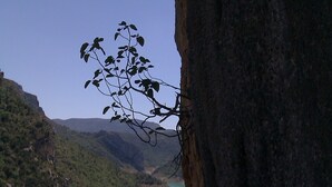 A rocky cliff overlooking a turquoise river with a wooden bridge. - Casa El Pelaire (Perarrua)