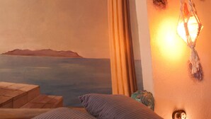 A bedroom with a bed, pillows, a wall-mounted lamp, and a mural of a landscape. - Casa El Pelaire (Perarrua)