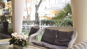Un canapé en osier avec des coussins, placé dans un espace intérieur bien éclairé et offrant une vue sur une cour.