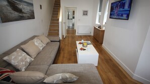A living room with a sofa, coffee table, and a painting on the wall. - Holiday Home With Hot Tub & Sauna (Bournemouth)