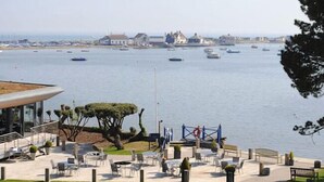 A waterfront area with outdoor seating, a small garden, and a view of the sea and boats. - Holiday Home With Hot Tub & Sauna (Bournemouth)