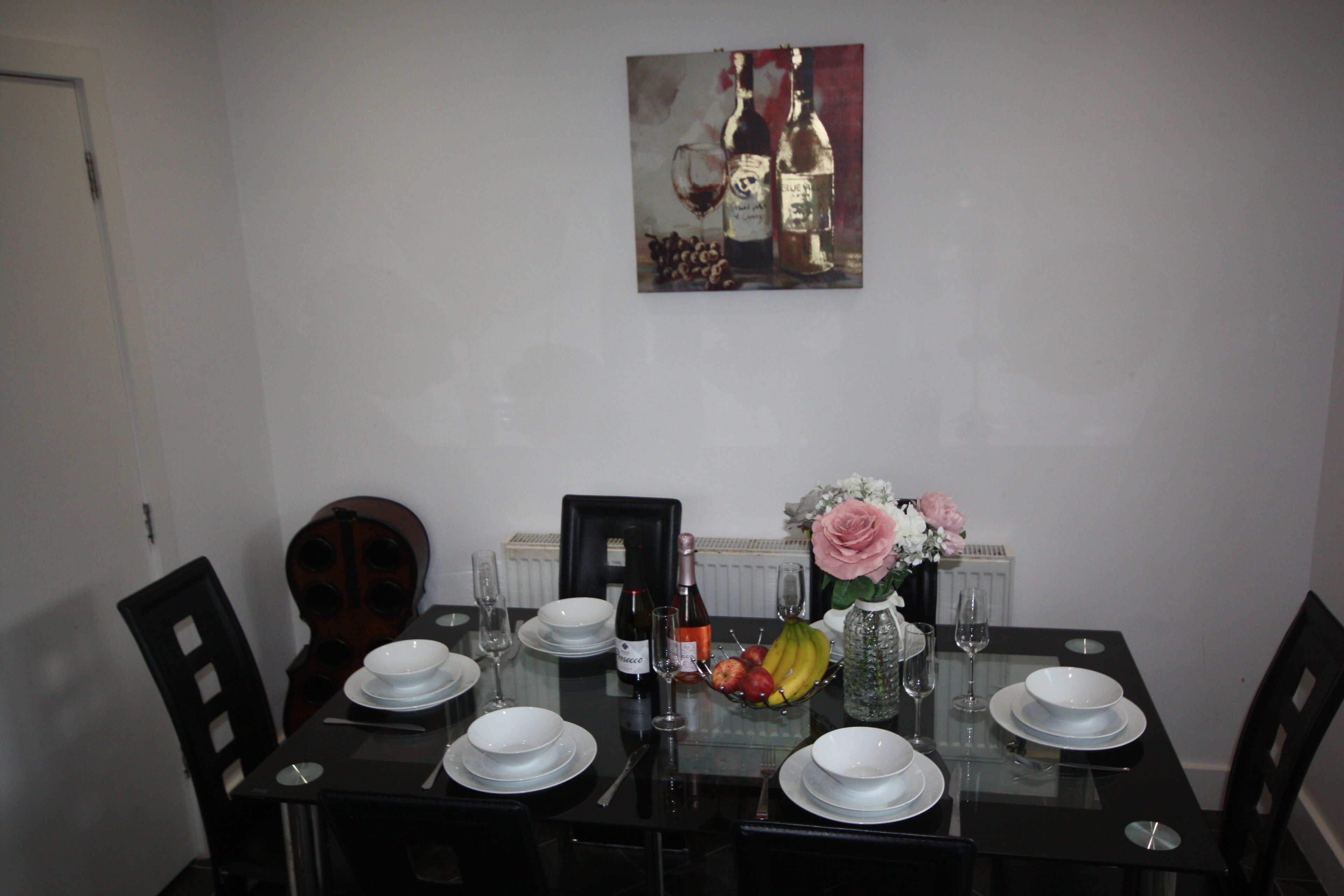 A dining table set with plates, glasses, and a fruit bowl.