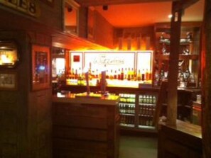 A bar area with a counter and shelves of bottles. - Waterford Lodge Hotel (Morpeth)