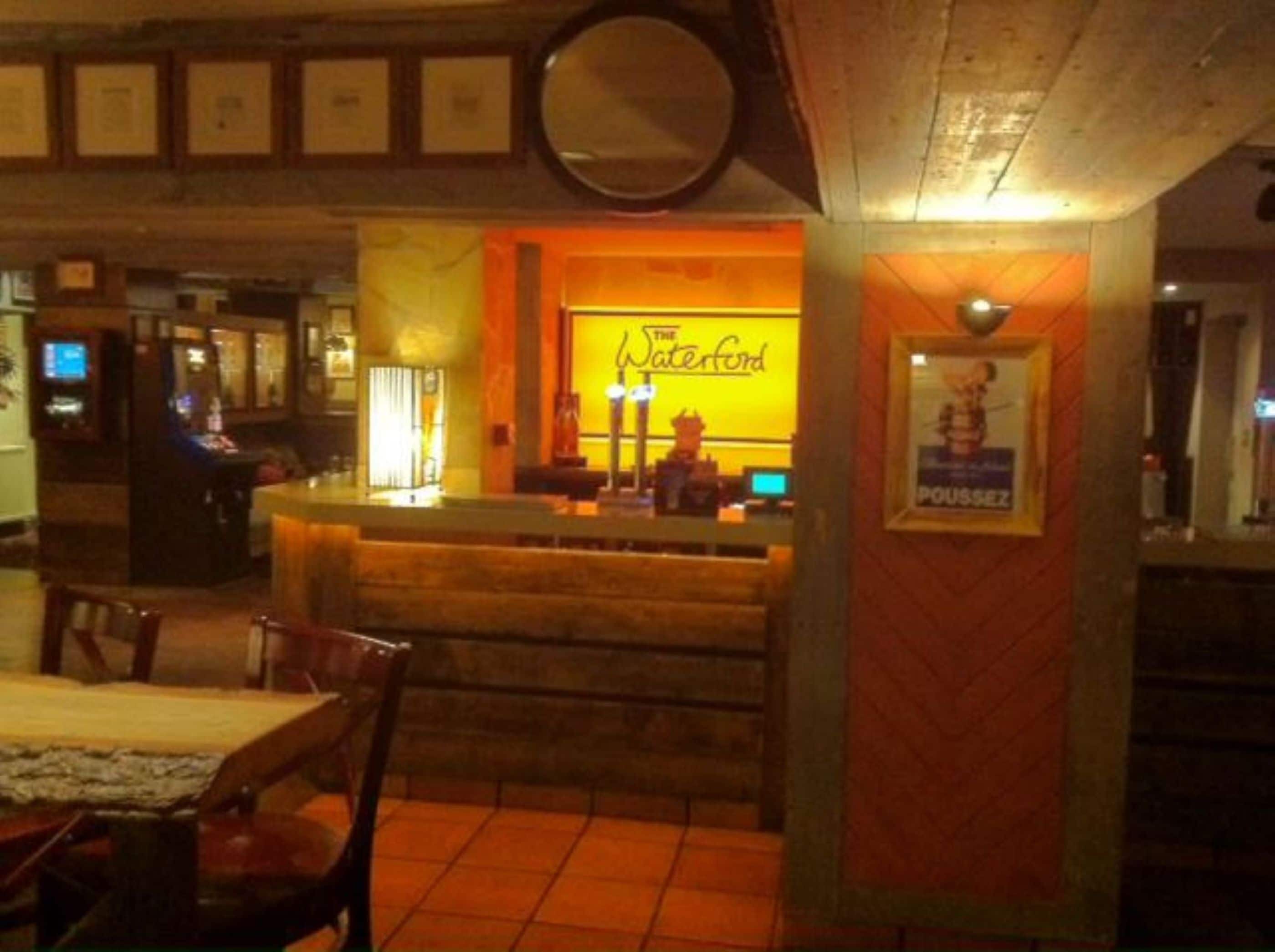 A bar area with a counter, a mirror above it, and a poster on the wall.