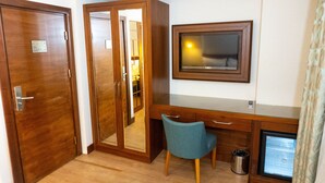 A hotel room with a wooden desk, a television, a chair, and a wardrobe. - Long Stay İstanbul Hotel (Istanbul)
