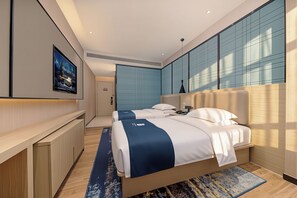 Une chambre d’hôtel moderne équipée d’un grand lit, d’un bureau et d’un téléviseur fixé au mur.