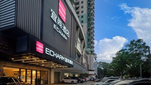 A hotel with a prominent ECHARM sign, a modern facade, and a parking area with several cars. - Echarm International Hotel Canton Tower Pazhou Convention and Exhibition Center Lujiang Metro Station Branch - Free Shuttle Bus to Canton Fair Complex During Canton Fair Period  (Guangzhou)
