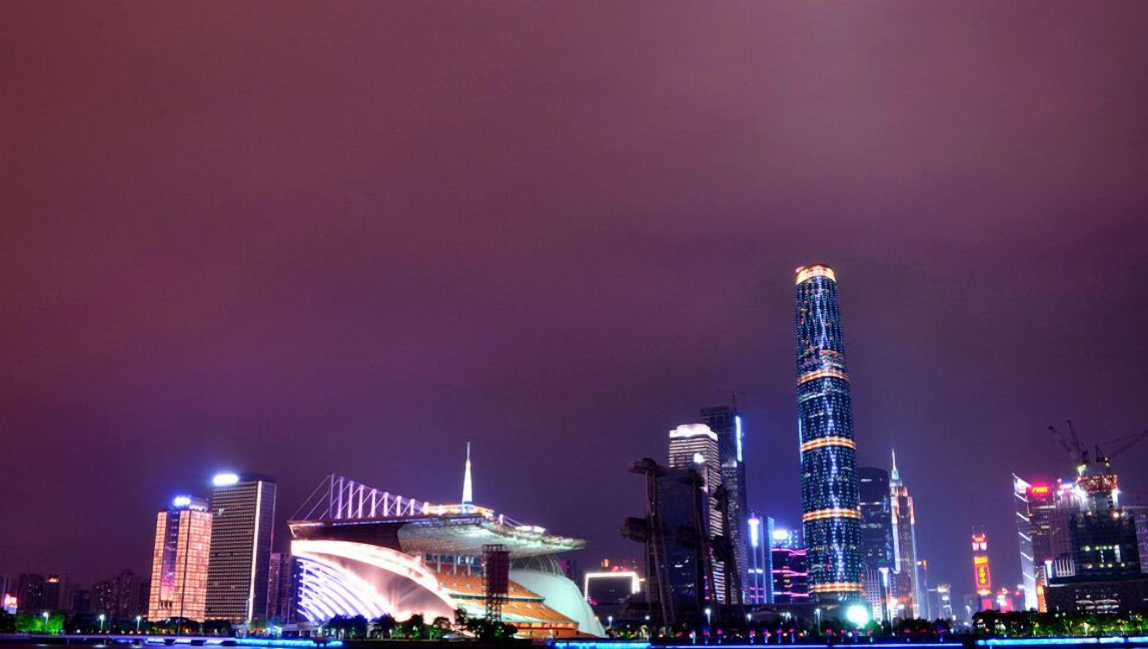 A city skyline at night with illuminated buildings and a prominent tower.