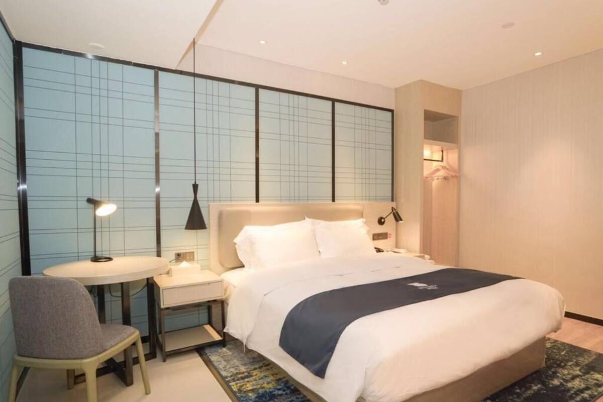 Une chambre d’hôtel moderne, dotée d’un grand lit, d’un bureau et d’une chaise.