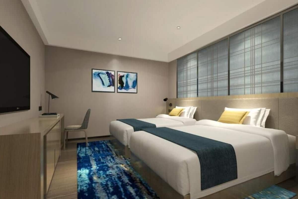 Une chambre d’hôtel moderne équipée de deux lits, d’un bureau, d’une chaise et d’œuvres d’art accrochées au mur.