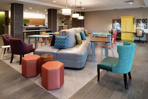 Ein moderner Lounge-Bereich mit einer Couch, Poufs, Sesseln und Tischen.
