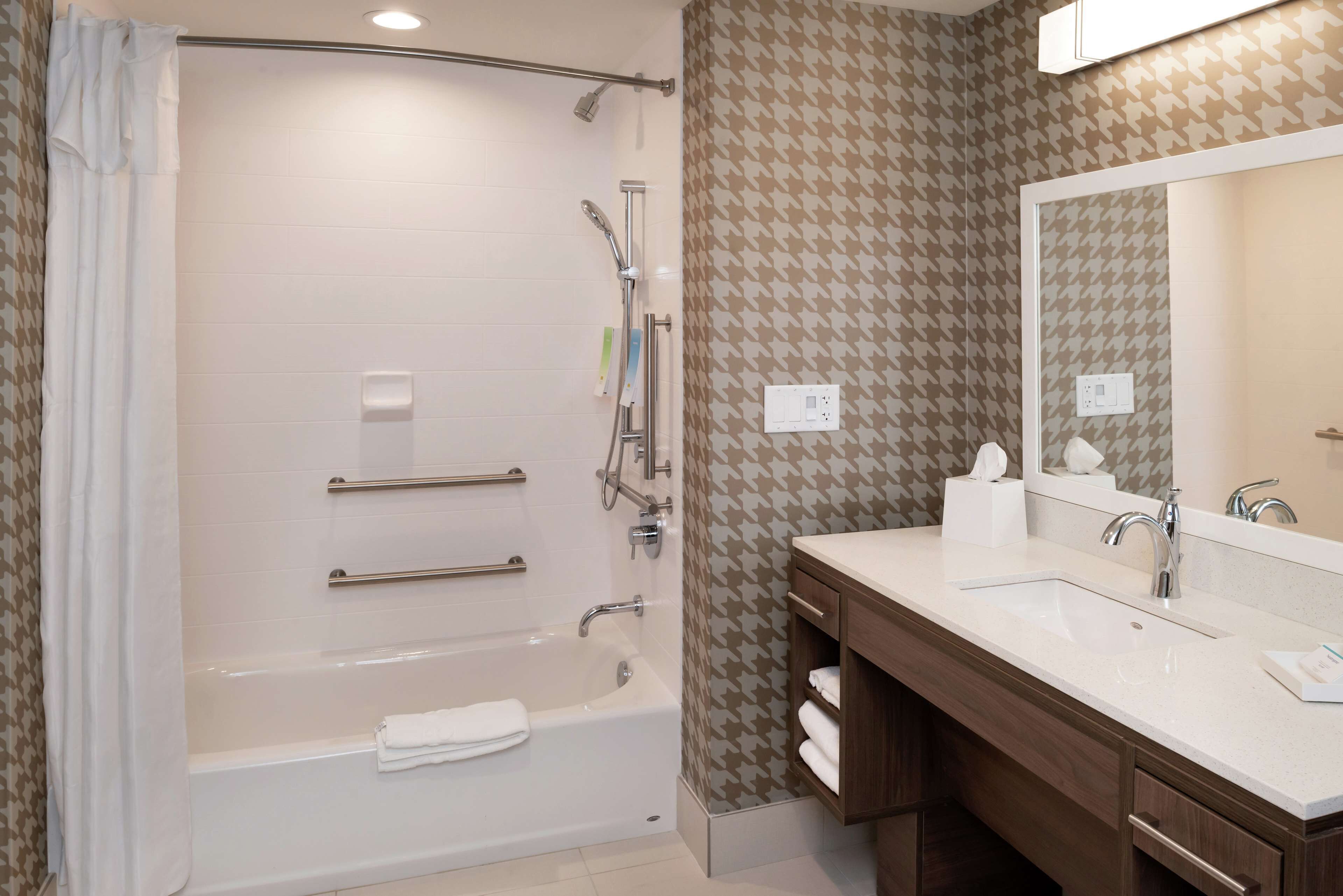 Une salle de bain moderne équipée d’une baignoire, d’une douche et d’un meuble-lavabo avec un miroir.