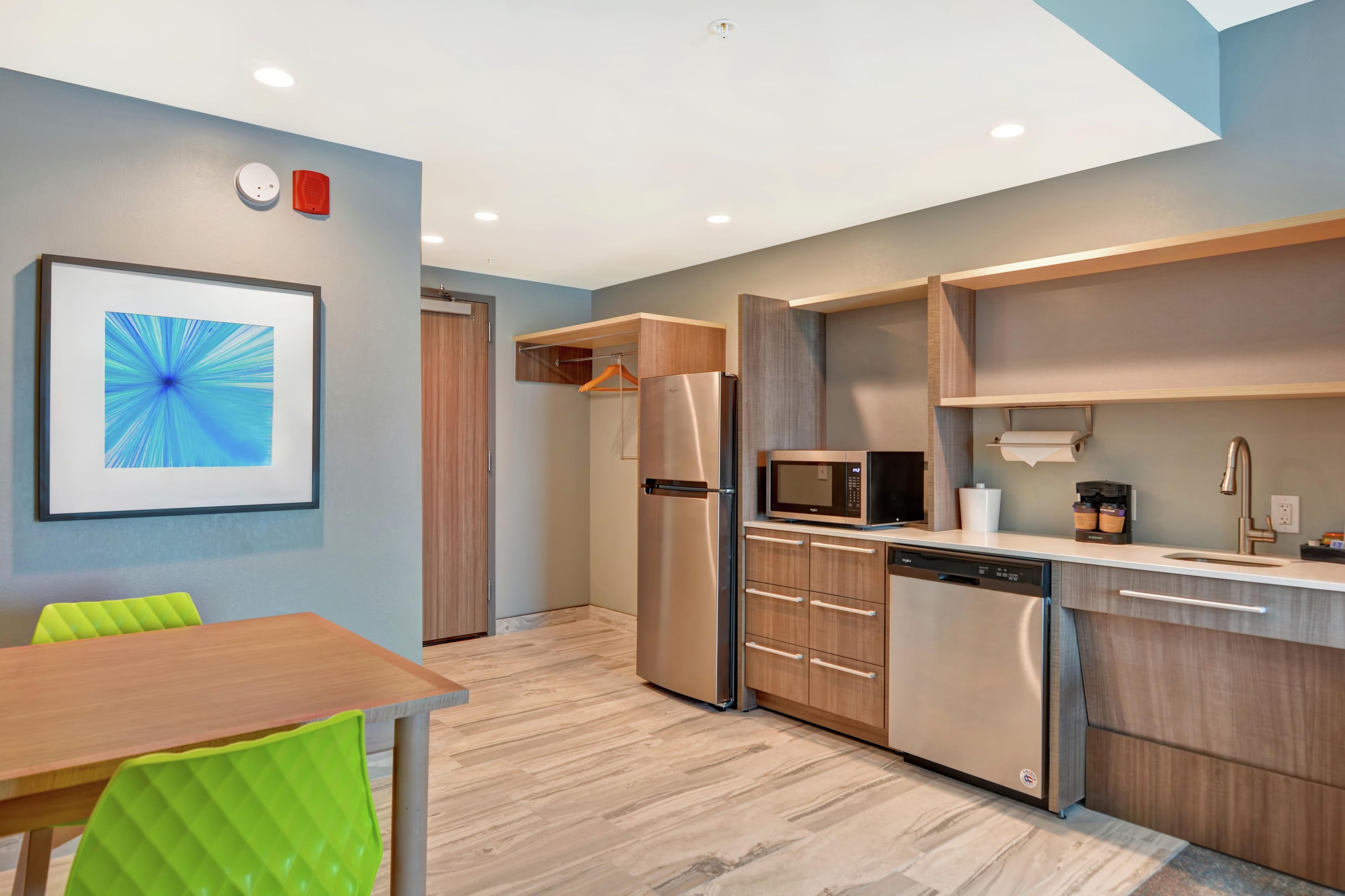 A modern kitchen with built-in appliances, a dining area with a table and chairs, and a framed picture on the wall.