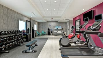 Academia com esteiras, pesos e bolas de exercício.