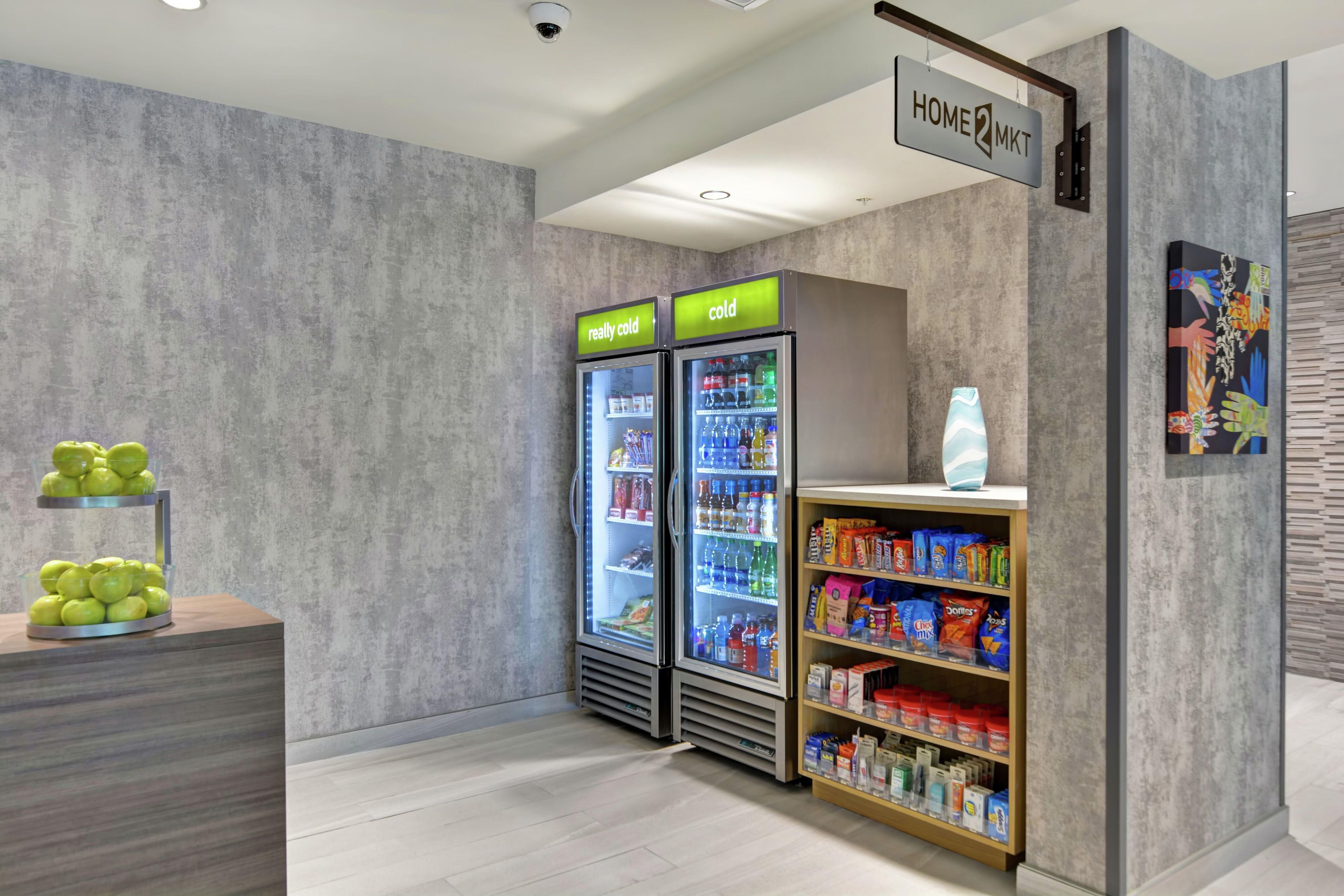 Una kitchenette moderna con un refrigerador de dos puertas, una máquina expendedora y un estante para aperitivos.
