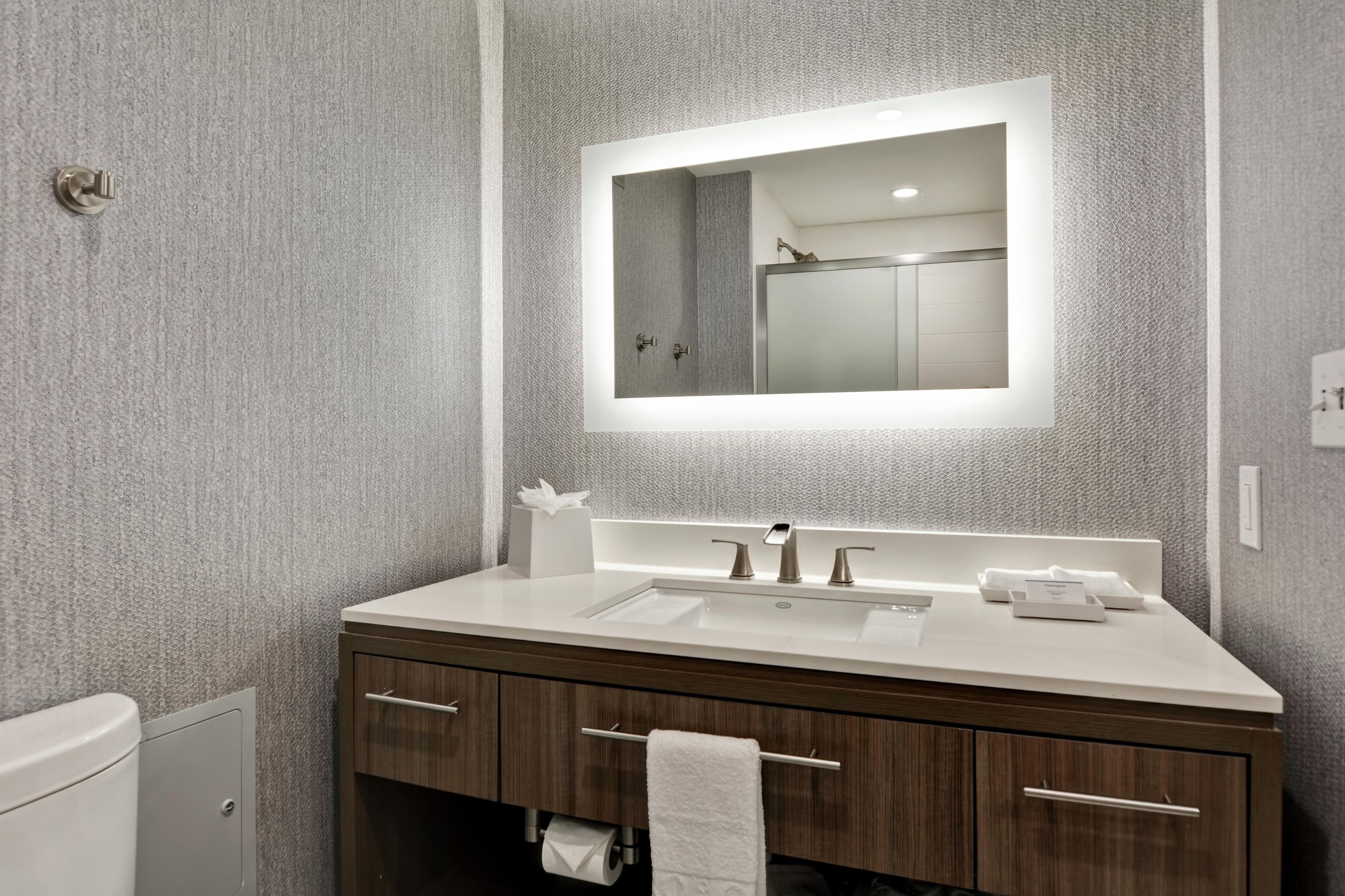 Un baño moderno con un espejo grande, un lavabo y un inodoro.