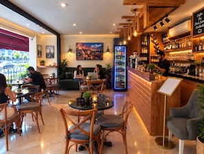 Un café avec des meubles en bois, un coin bar et un tableau représentant un paysage urbain accroché au mur.