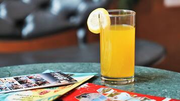 A glass of orange juice with a lemon slice on a table with brochures.