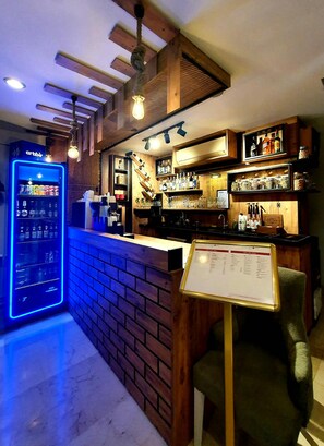 A bar area with a brick counter, shelves with bottles, and a menu stand. - Taximtown Hotel (Istanbul)