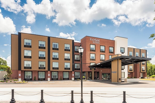 A multi-story hotel with a brick facade, large windows, and a covered entrance area.