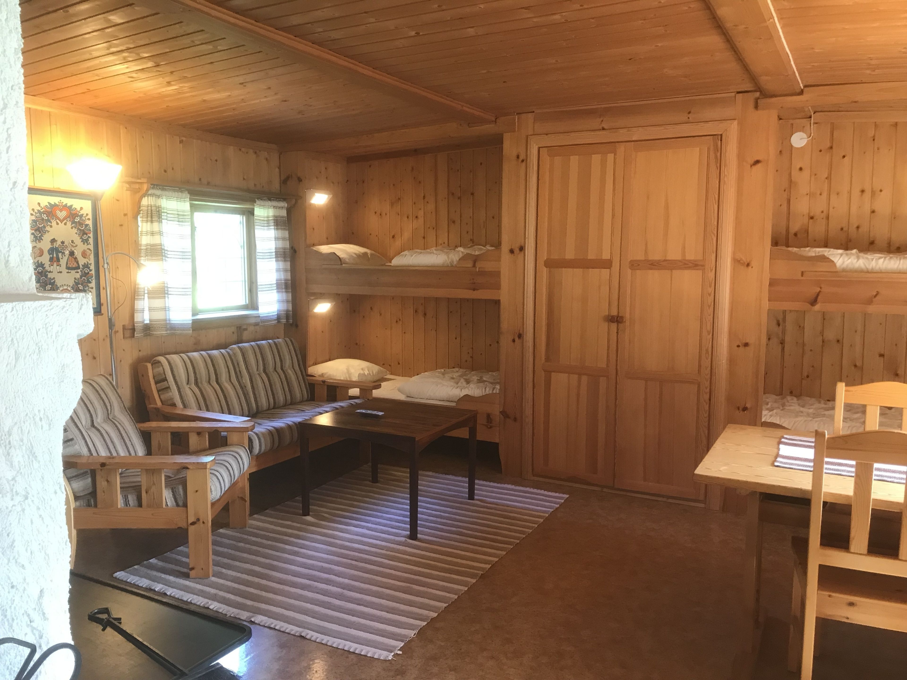 A cozy cabin interior with a sofa, a table, and a bunk bed.