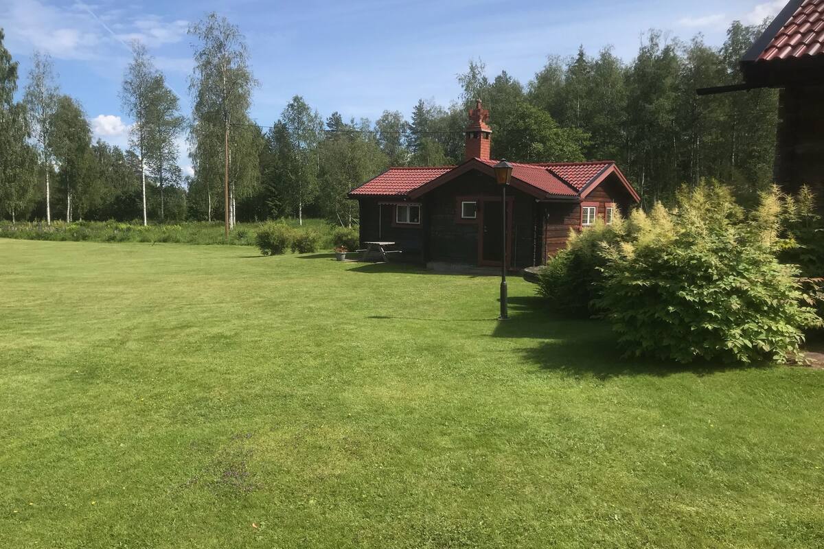A house with a red roof, surrounded by a grassy yard and trees.