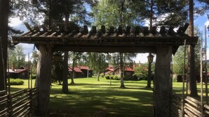 Puinen pergola, joka on rakennettu puistoon, jossa on nurmikko ja puita.