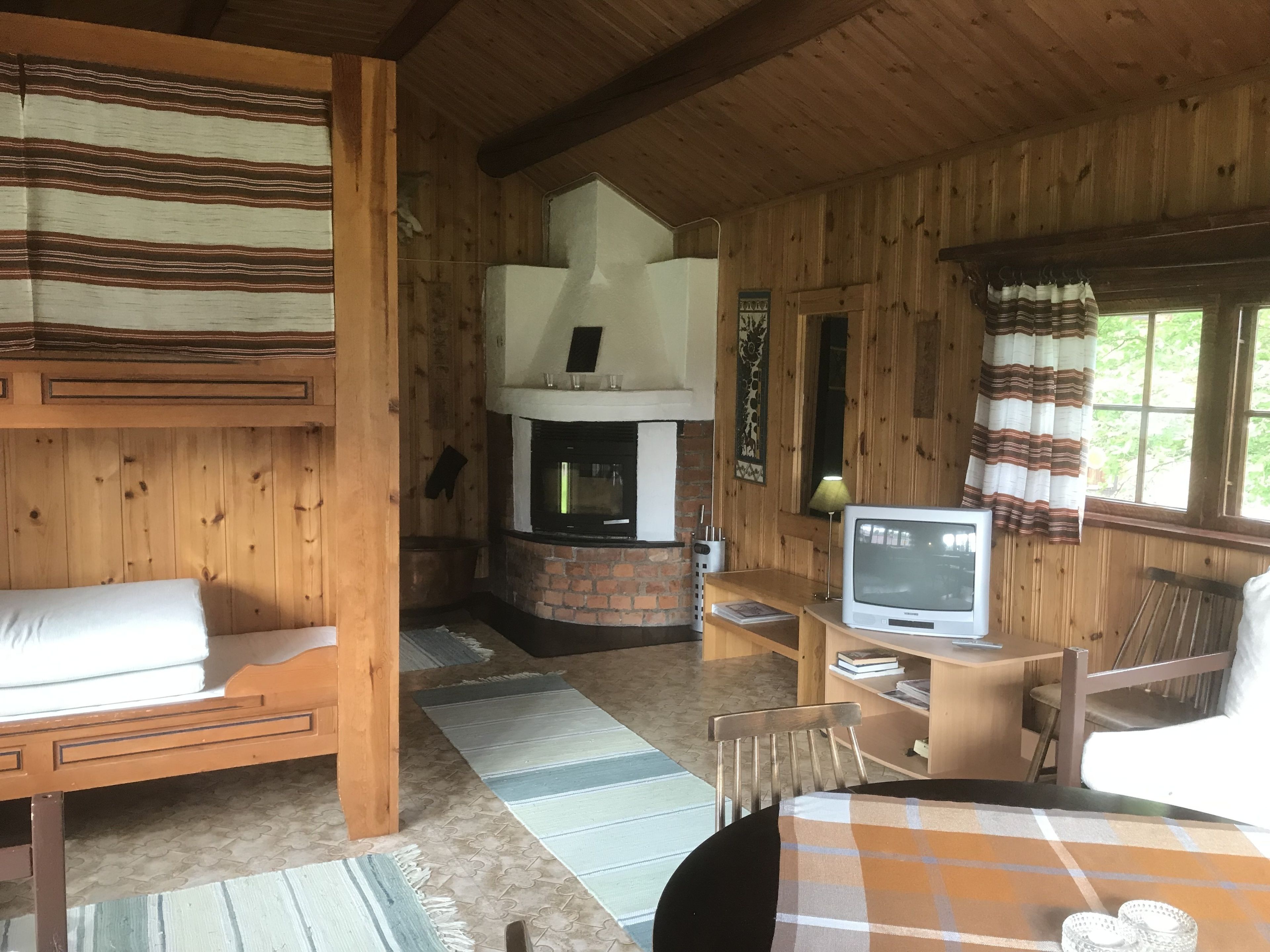 Un interior de cabaña acogedor con chimenea, paredes de madera, un sofá, un televisor y un comedor.