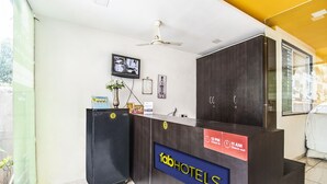 A hotel reception desk with a sign reading "TabHotels" and a clock indicating check-in times.