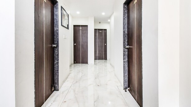 A hallway with three dark wooden doors, each marked with a number. The floor is tiled with white marble.