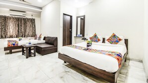 A hotel room with a bed, a sofa, a small table, and a mirror.