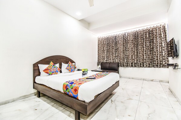 Une chambre d’hôtel moderne avec un grand lit, une télévision et un rideau à motifs.
