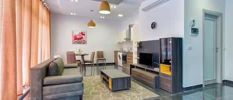 Una sala de estar moderna con sofá, televisor y comedor.