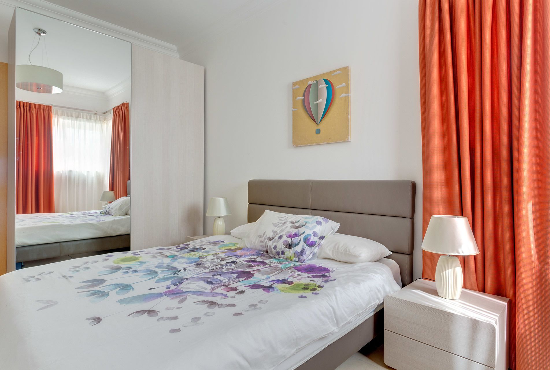 Une chambre d’hôtel avec un lit, une table de chevet, une lampe, un miroir et un tableau au mur.