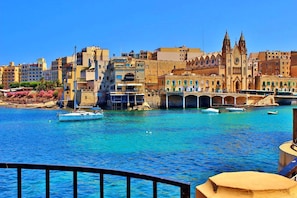 A coastal cityscape with a prominent church, a bridge, and boats on the water. - Seaview 3BR Apart inc Pool, Fort Cambridge Sliema (Sliema)