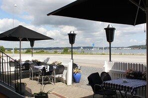 An outdoor patio with tables and chairs, a view of a body of water, and a white picket fence. - Sølyst Kro (Aabenraa)
