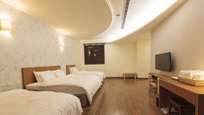 A hotel room with two beds, a desk, a television, and a window. - Footprint Inn (Jiji)