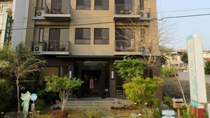 A multi-story building with balconies, a gated entrance, and a landscaped front yard. - Footprint Inn (Jiji)