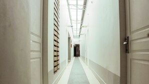 A long, narrow hallway with white walls and a tiled floor, leading to a door at the end. - RedDoorz Plus near UV Mandaue Cebu (Mandaue)