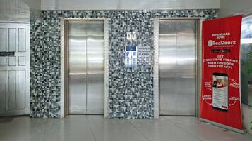 A hotel elevator with a mosaic tile wall and a RedDoorz promotional poster.