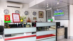 A reception desk with clocks, a sign for New Era Budget Hotel, and a QR code. - RedDoorz Plus near UV Mandaue Cebu (Mandaue)