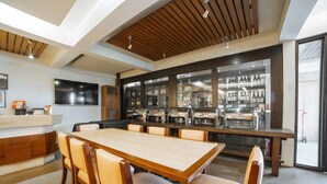 Un comedor moderno con una mesa y sillas de madera, una cocina con un expositor de vidrio y un ventanal grande.