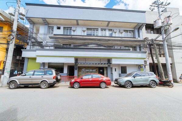 A building with multiple floors, a storefront, and parked cars.