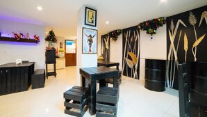 A modern interior with a wooden table and stools, a Christmas tree, and wall art. - RedDoorz Plus near San Pedro Cathedral (Davao)