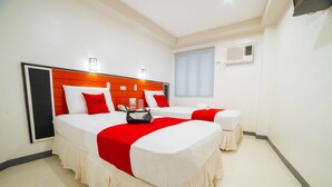 A hotel room with two beds, each with a red and white bedspread, a wooden headboard, and a bedside table with a lamp. - RedDoorz Plus near San Pedro Cathedral (Davao)
