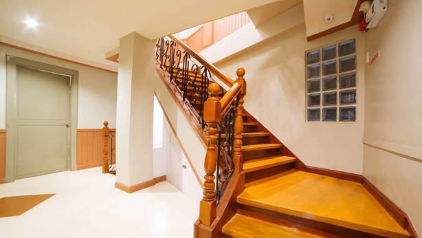A wooden staircase with a metal railing leading to a landing. - RedDoorz Plus near San Pedro Cathedral (Davao)