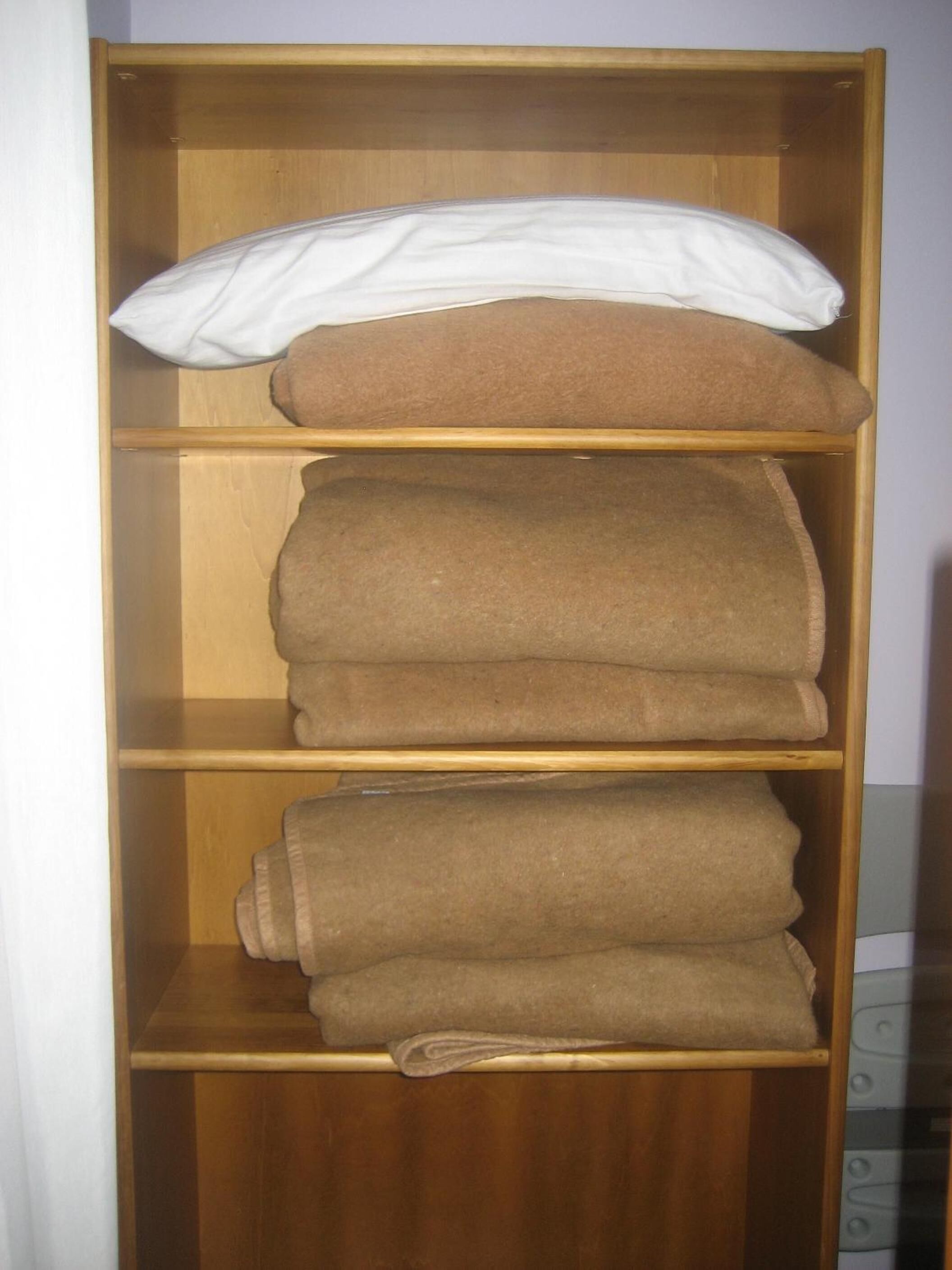 Une étagère en bois à trois niveaux, chaque niveau servant à ranger des serviettes pliées.